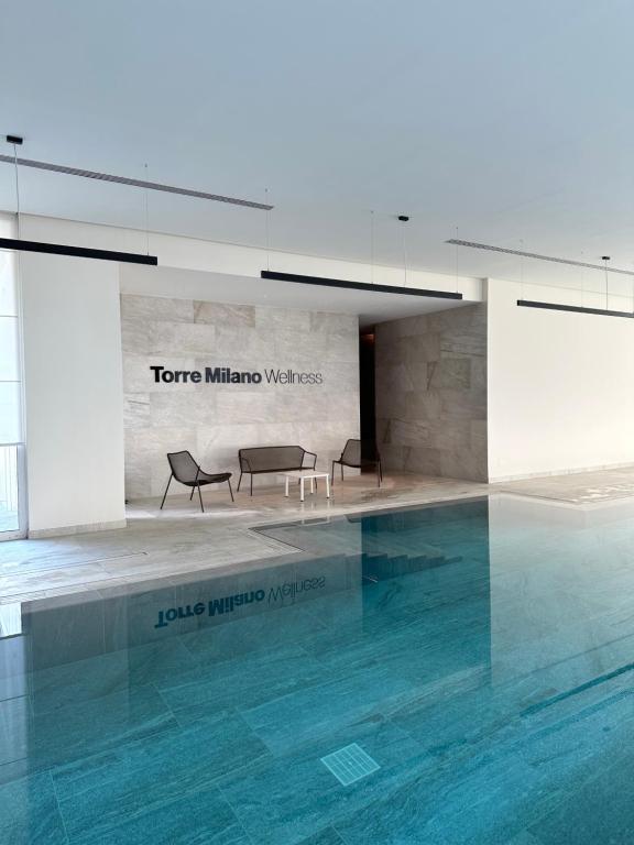 米兰Torre Milano - Luxury modern flat的大楼内一个带两把椅子和一张桌子的游泳池
