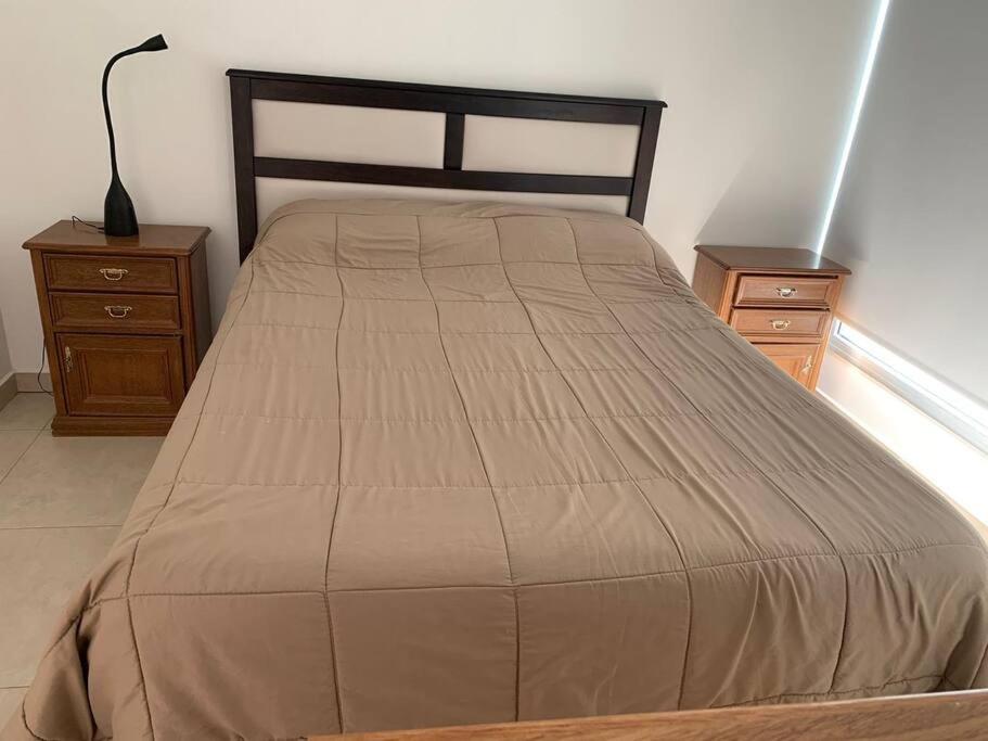 玛德琳港Hermoso depto en excelente ubicacion的卧室内的一张床位,配有两个床头柜和一盏灯