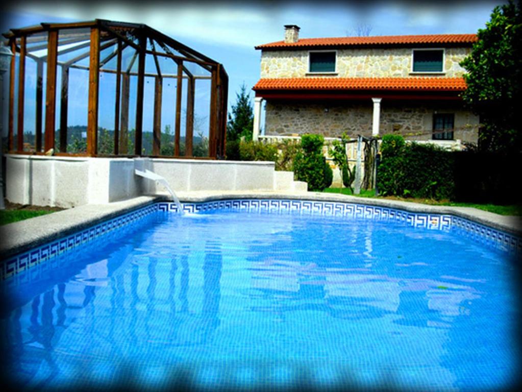 庞特维德拉Casa Rural Os Carballos的一座大蓝色游泳池,位于房子前