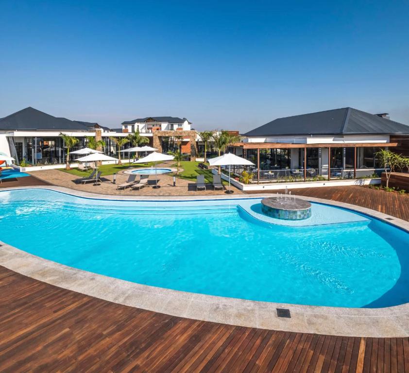巴利托BALLITO HILLS, 1 bedroom apartment的度假村内的大型游泳池,配有桌子和遮阳伞