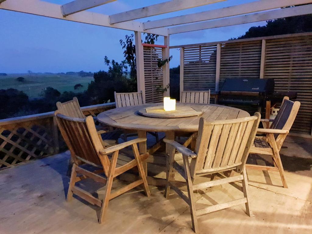 NgatakiTealuca Holiday Home的一张带椅子的木桌和甲板上的蜡烛