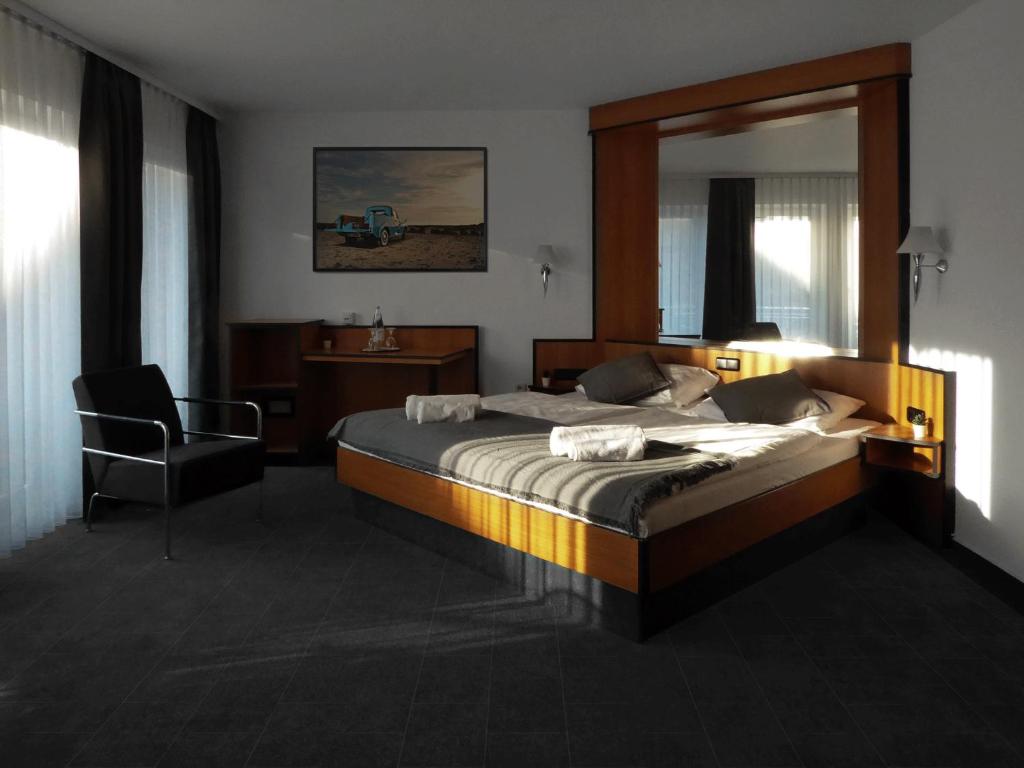 韦特海姆Hotel am Malerwinkel的一间卧室配有一张带镜子和椅子的床