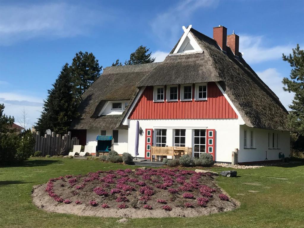 维克Landhaus Kranichblick的茅草屋顶和花床的房子