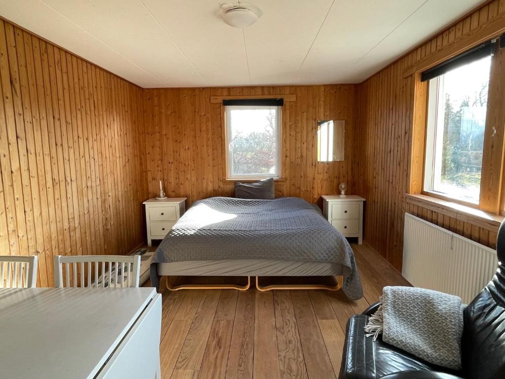 TroenseEskærhus på Tåsinge, tæt på Svendborg - Afdeling med egen indgang的卧室配有一张床铺,位于带木墙的房间内
