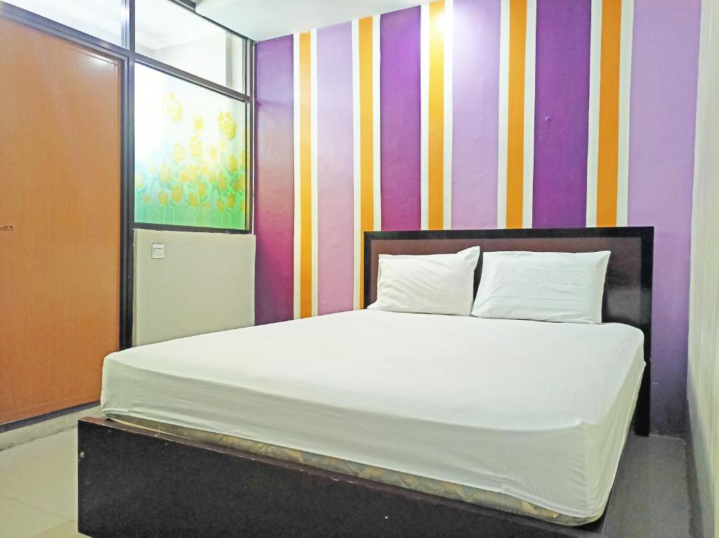 NunukanOYO 92126 Hotel Syariah Sumber Mulya Nunukan的一张位于多彩墙上的床铺