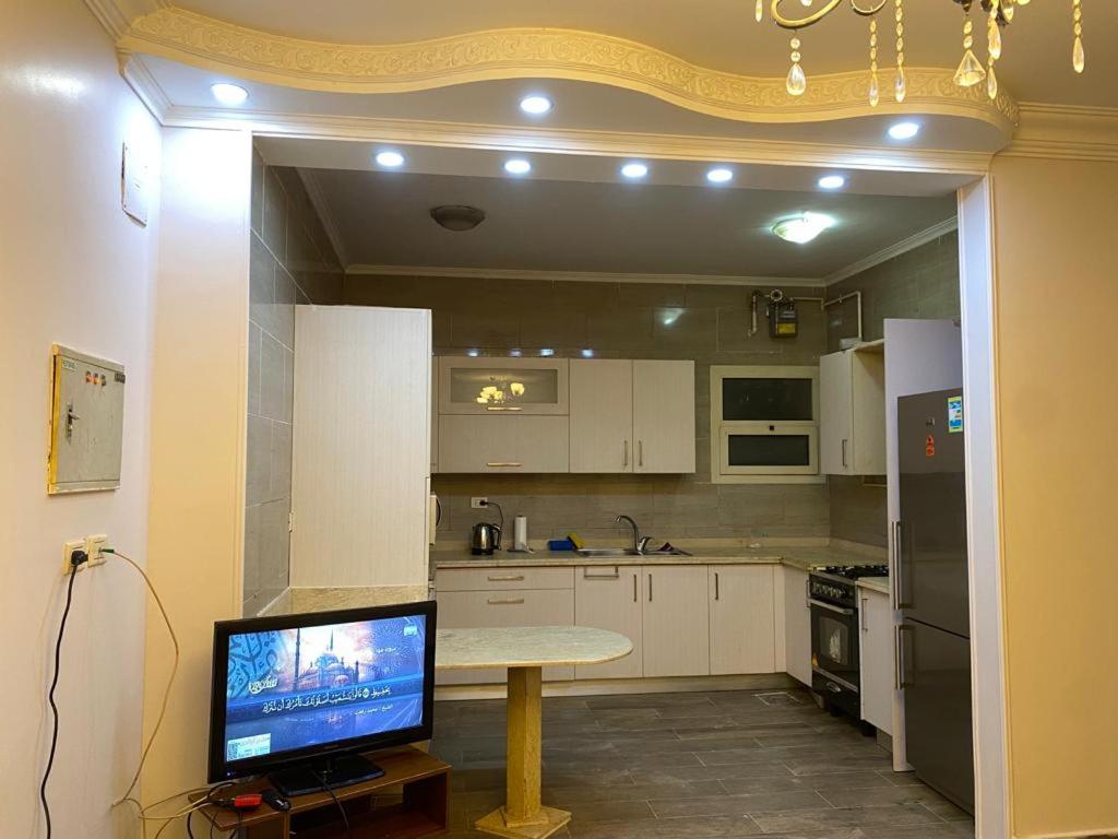 马迪纳特阿什舒鲁克Heliopolis Residence Shrouk city Cairo的厨房配有桌子和电视机