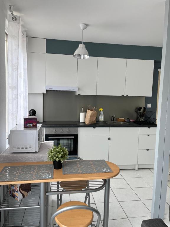 塞纳河畔维尼厄Belle maison的厨房配有白色橱柜和桌椅