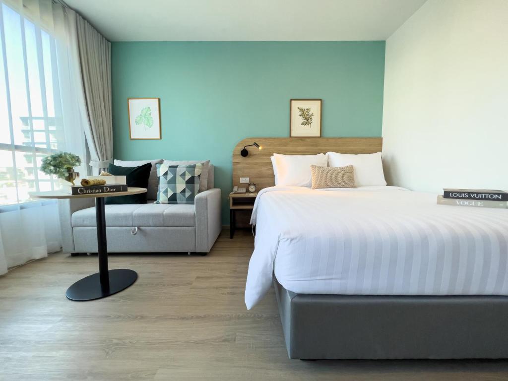 曼那Wellness Stay & Hotel Sukhumvit 107的一间卧室配有一张床和一张沙发