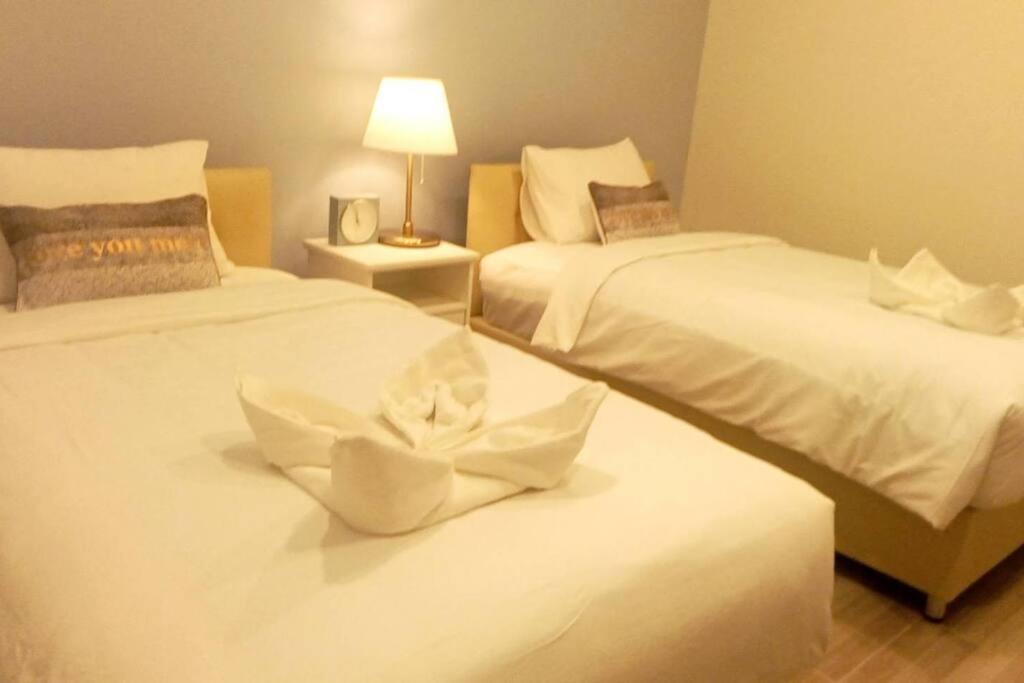 尖竹汶Na - cha - lae (3)的一间卧室配有两张带白色床单和灯的床