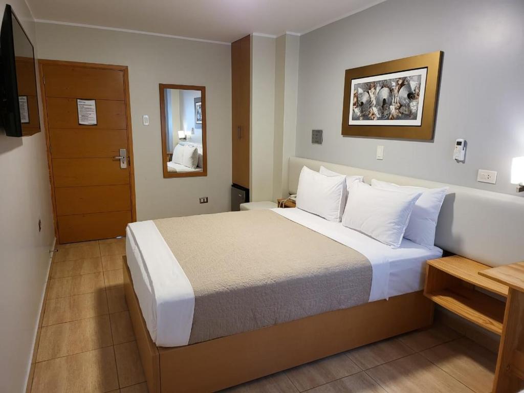瓦乔Hotel Punta Rocas - Huacho的配有一张大床和镜子的酒店客房