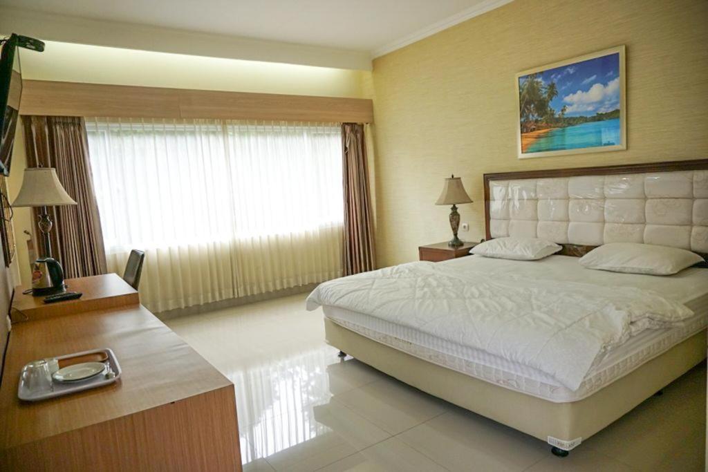 茂物Griya Kayana Inn and Villas的一间卧室设有一张大床和一个大窗户