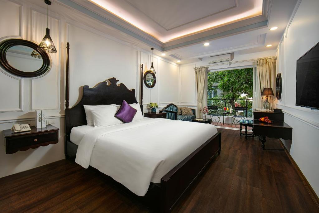 河内San Boutique Hotel的卧室配有一张白色大床和紫色枕头