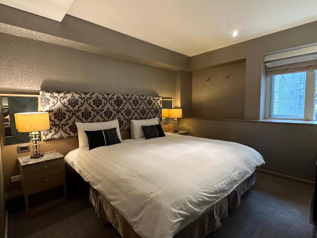 台北銀座飯店Ginza Hotel的一间卧室配有一张带两盏灯的大型白色床。