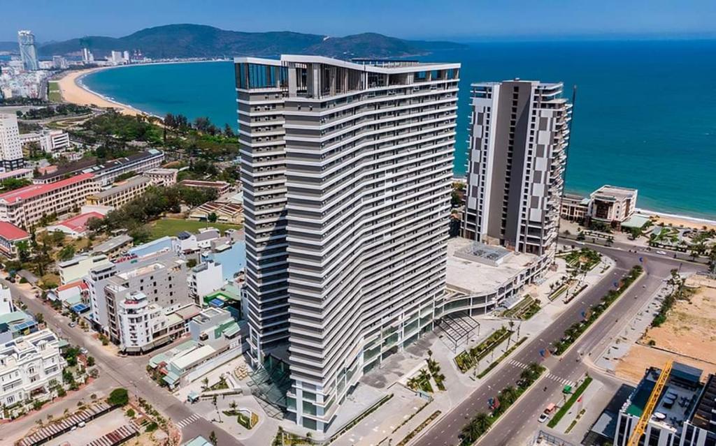 归仁Glese Balcony Seaview Apartment - FLC Sea Tower Quy Nhon的海滩旁白色大建筑的空中景色