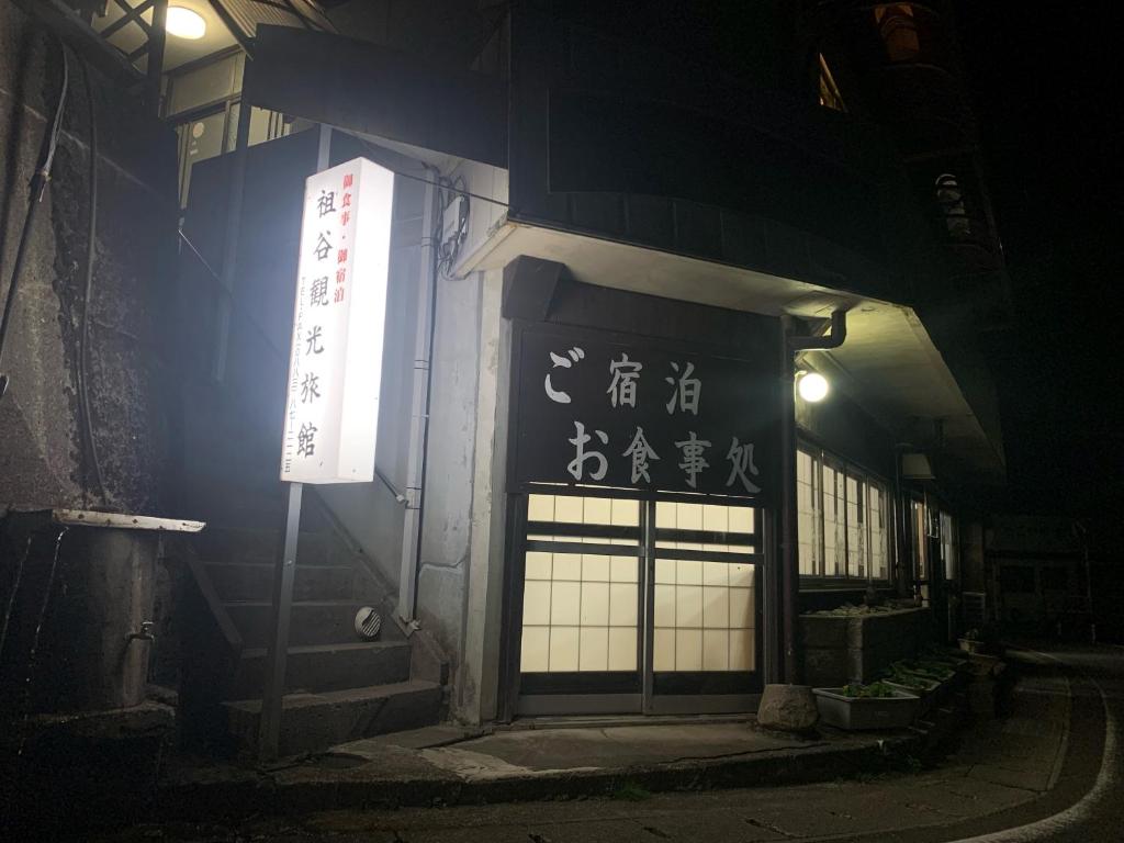 三好市Iya Kankou Ryokan的一座建筑物,晚上在建筑物的一侧有标志