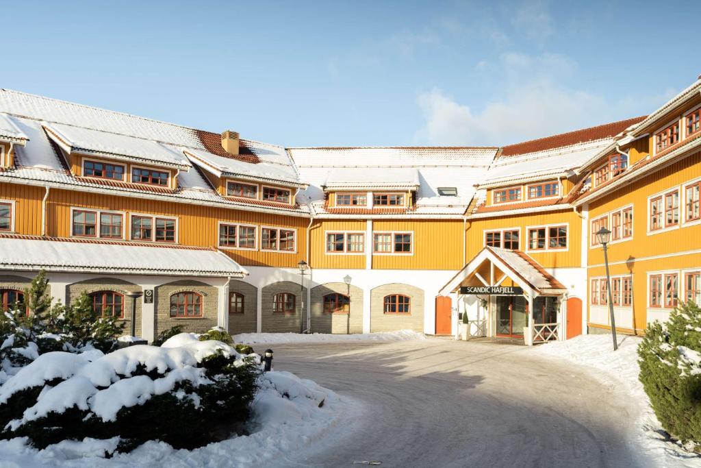 哈山哈山斯堪迪克酒店的一座黄色的大建筑,上面有雪