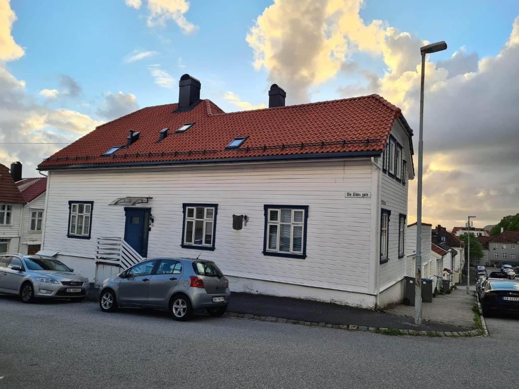 卑尔根Fløyen Townhouse的一座白色的房子,前面有汽车停放