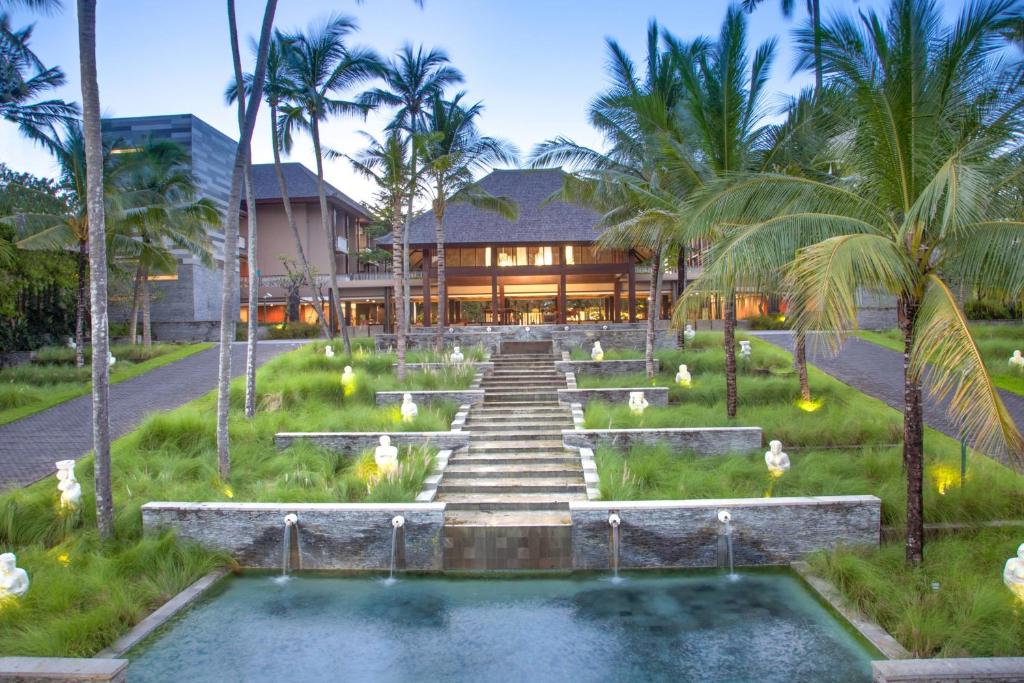 努沙杜瓦巴厘岛努沙杜瓦万怡度假酒店的一座带游泳池的度假村,位于一座建筑前