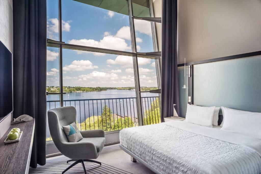 汉堡汉堡艾美酒店的一间卧室配有一张床、一把椅子和一个大窗户