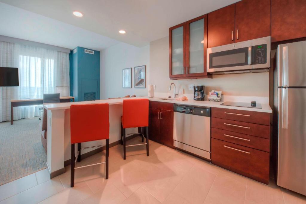 罗利罗利市区万豪旗下原住客栈的厨房配有木制橱柜和红色椅子