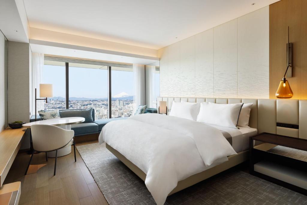 横滨The Westin Yokohama的卧室配有一张白色大床、一张书桌和一张沙发。