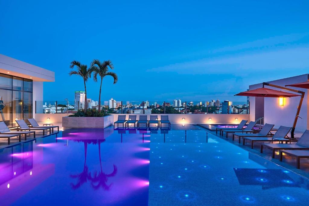 圣克鲁斯圣克鲁斯西拉万豪酒店的一座带椅子的游泳池,晚上则享有城市天际线