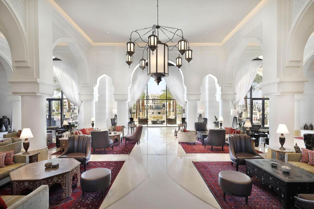 亚喀巴Al Manara, a Luxury Collection Hotel, Aqaba的大堂设有桌椅和吊灯。