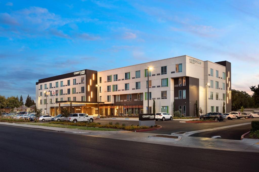 克洛维斯Courtyard by Marriott Fresno Clovis的停车场内停放汽车的大型建筑