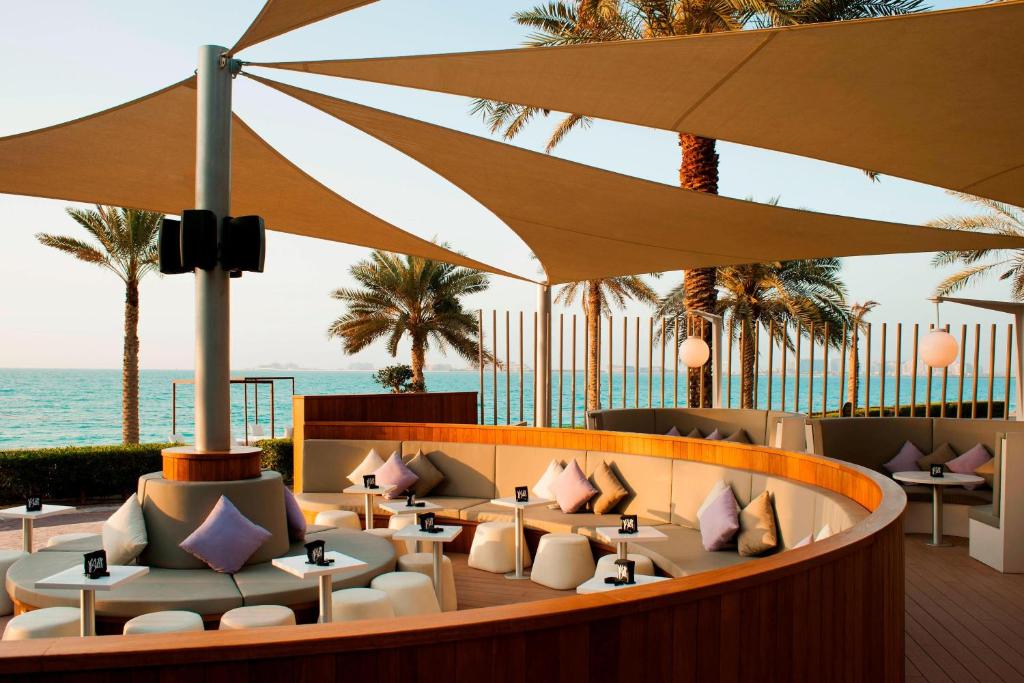 迪拜喜来登朱美拉海滩度假酒店的一间设有桌子和遮阳伞的餐厅,享有海景