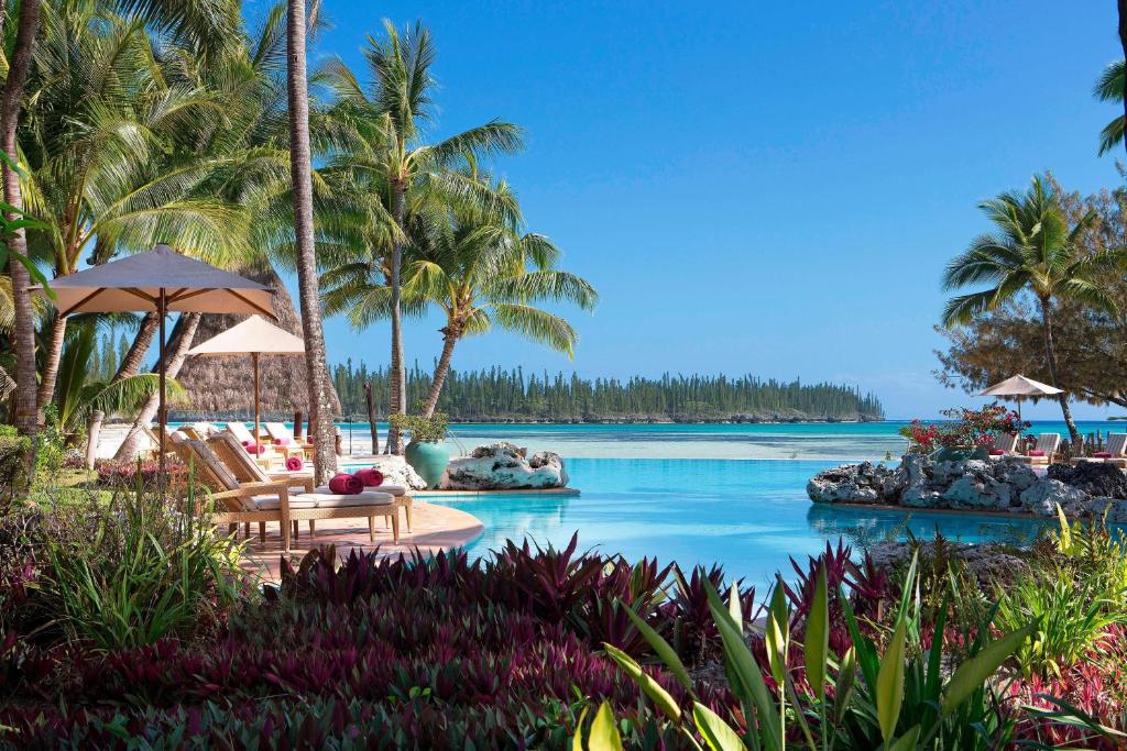 Oro Bay松林岛子午线度假酒店的一个带椅子和棕榈树的游泳池的度假酒店
