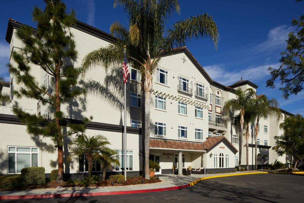 西湖村酒店洛杉矶西湖西昂村原住酒店的一座白色的大建筑,前面有棕榈树