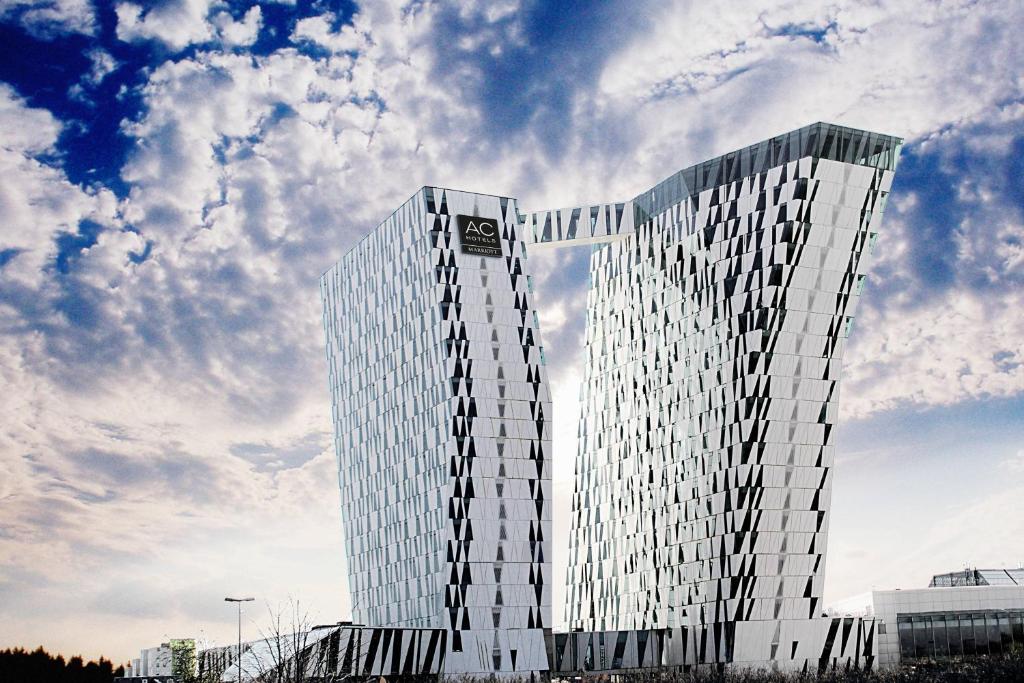 哥本哈根哥本哈根贝拉天空万豪AC酒店的一座高大的玻璃建筑,背后是天空