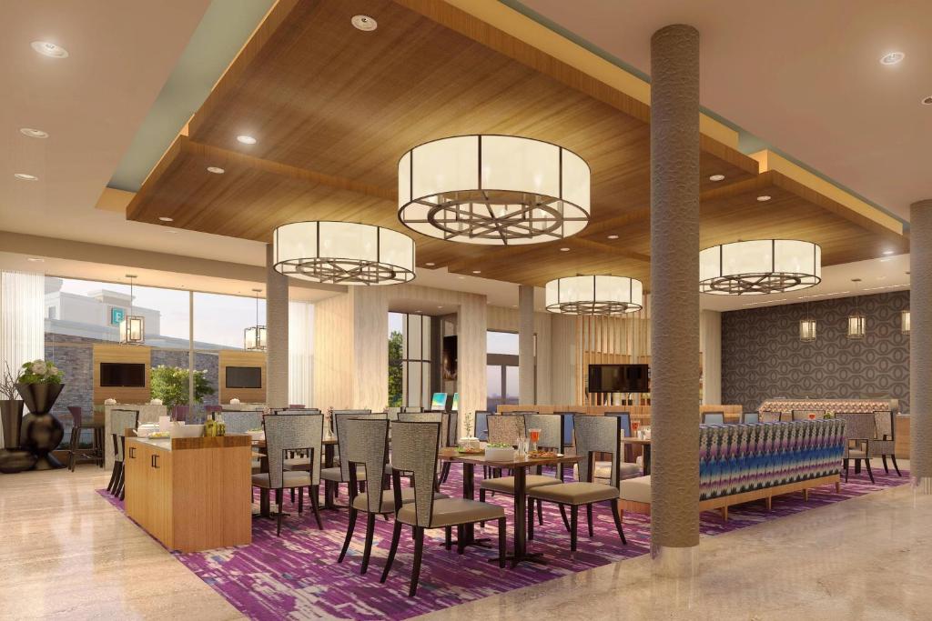 费耶特维尔SpringHill Suites by Marriott Fayetteville Fort Liberty的餐厅设有桌椅和吊灯。