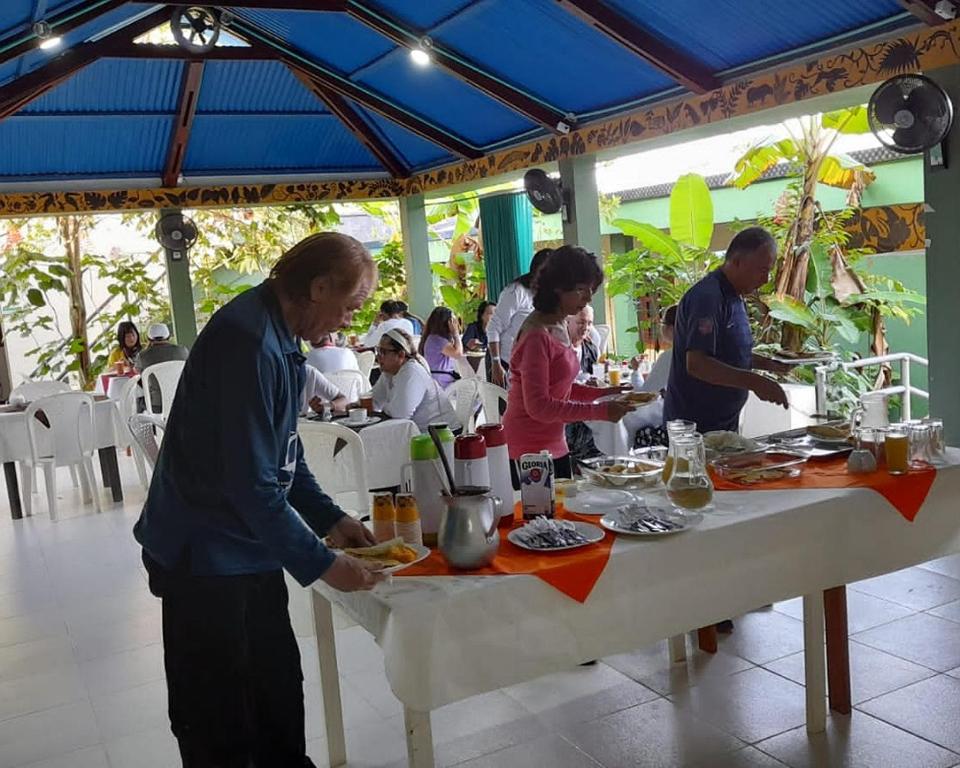 Puerto NariñoWikungo Hotel的一群坐在餐桌上吃食物的人