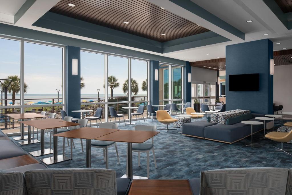 默特尔比奇SpringHill Suites by Marriott Myrtle Beach Oceanfront的有桌椅和窗户的大厅
