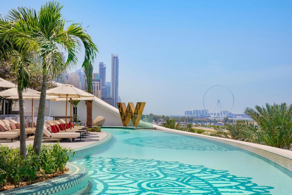 迪拜W Dubai - Mina Seyahi, Adults Only的一座带椅子和棕榈树的游泳池