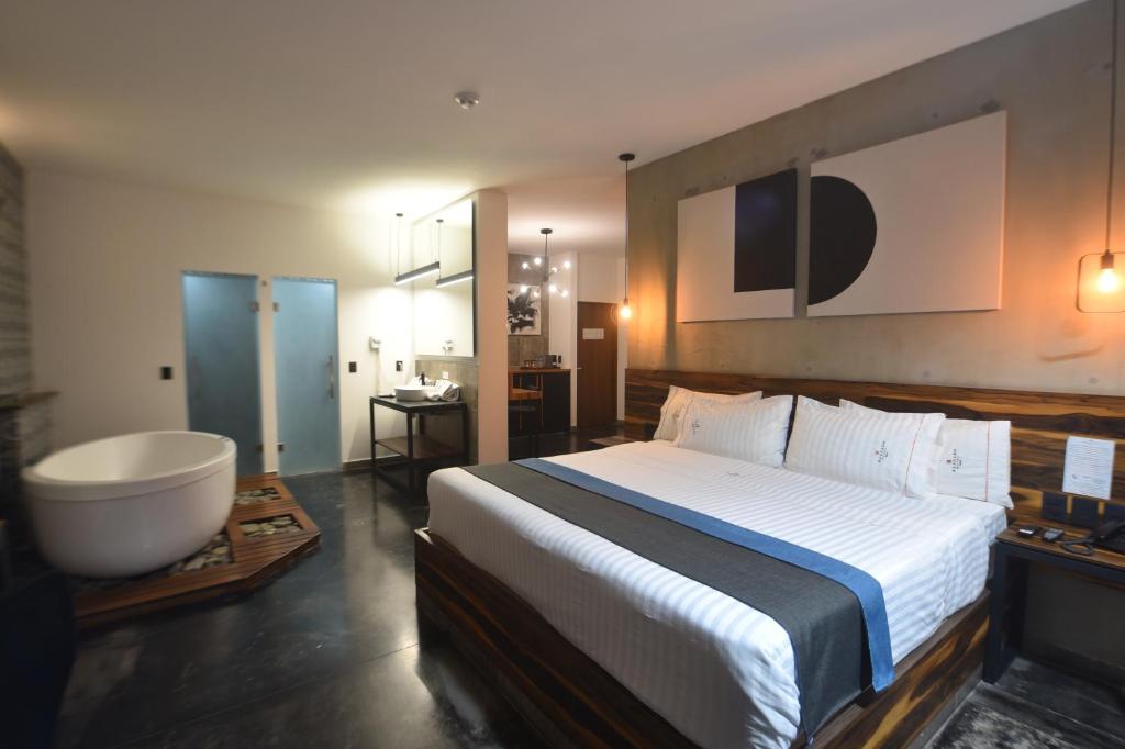 瓜达拉哈拉Hangar Inn Select Aeropuerto Guadalajara的一间卧室设有一张大床和一个浴缸