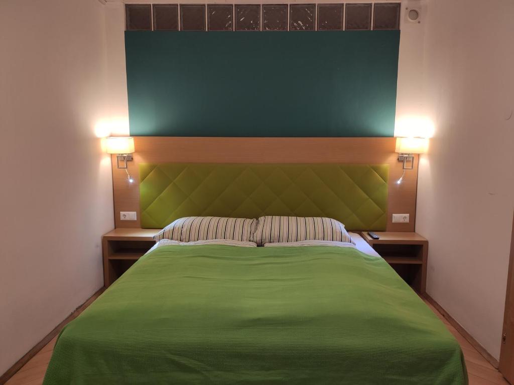 格拉茨Vintage Apartment的一间卧室配有绿床和两盏灯