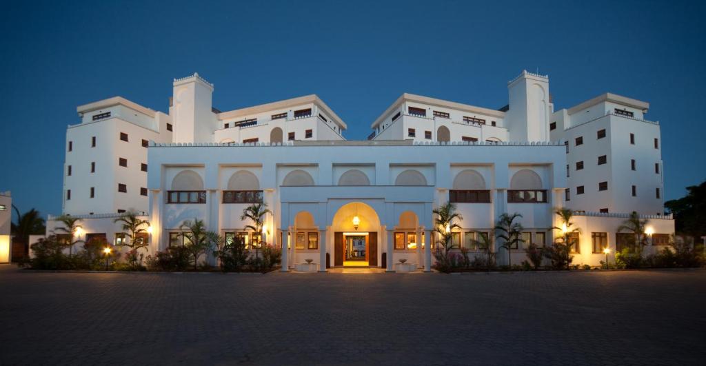 迪亚尼海滩马缨丹嘎鲁海滩酒店的一座白色的大建筑,晚上灯亮