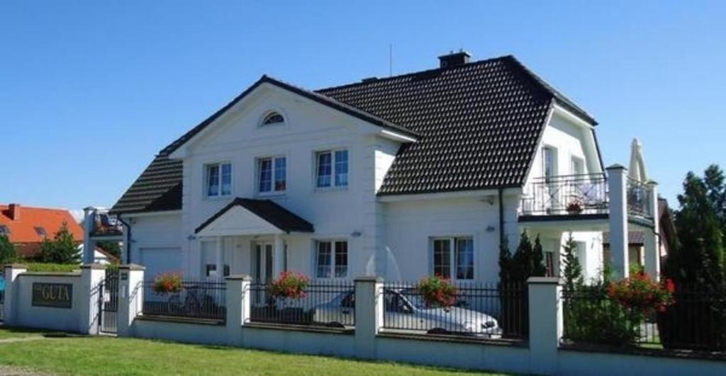 罗威Charmantes Appartement in Rowy mit Grill, Garten und Terrasse的白色的房子,有黑色的屋顶和栅栏