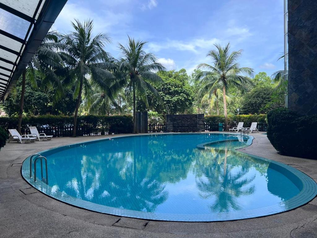 瓜埠RUMAH SINGGAH APARTMENT的一座种植了棕榈树的蓝色游泳池