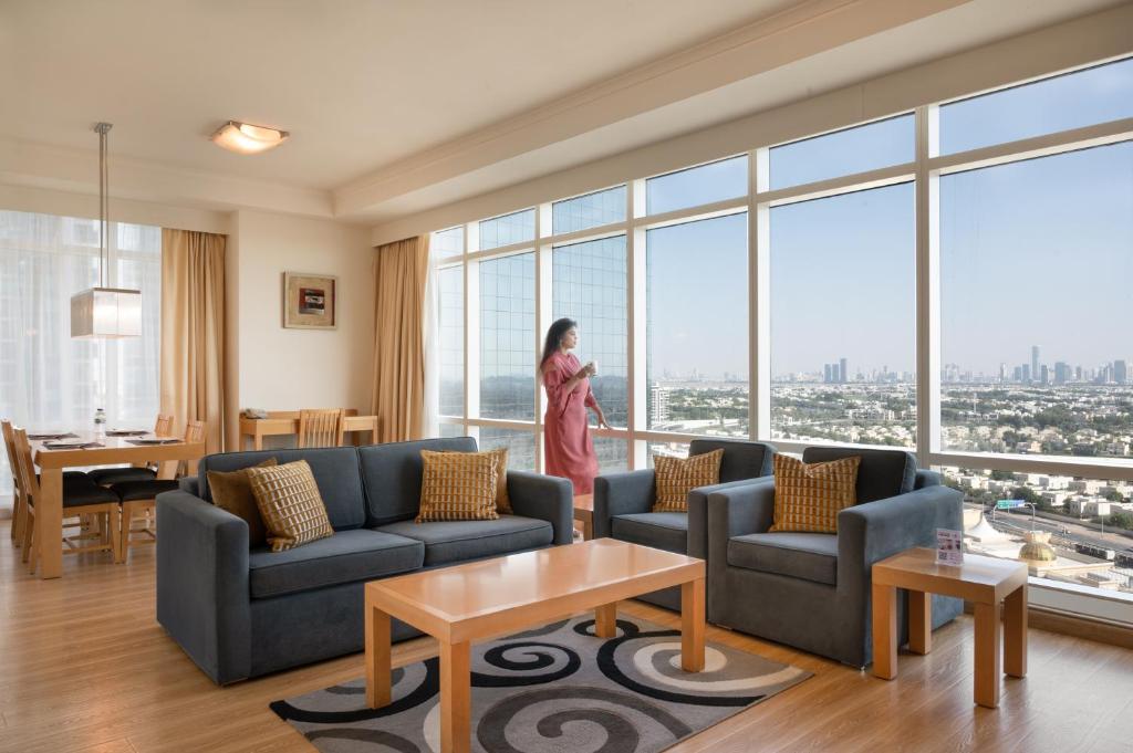 迪拜Oaks Liwa Heights Hotel Suites的站在带大窗户的客厅中的女人