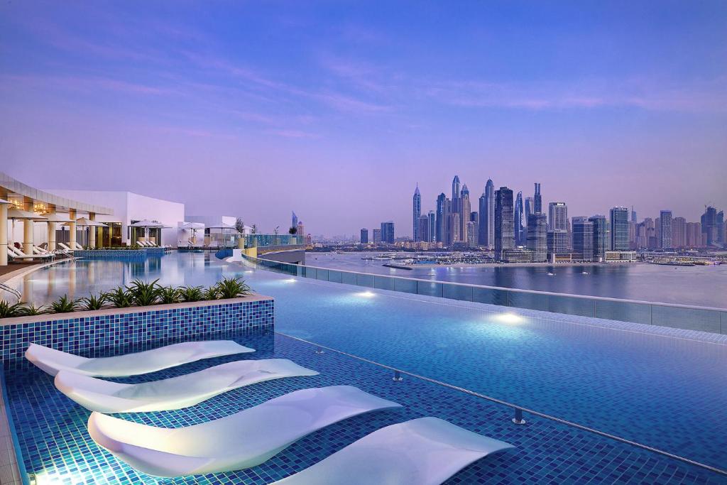 迪拜NH Collection Dubai The Palm的酒店游泳池享有城市景观