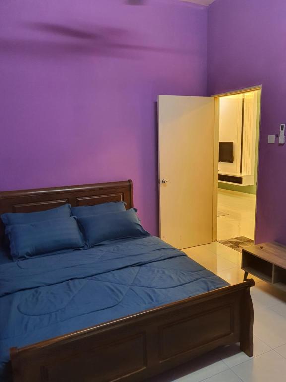 马西Homestay Layang的一间卧室设有紫色的墙壁和一张带蓝色枕头的床