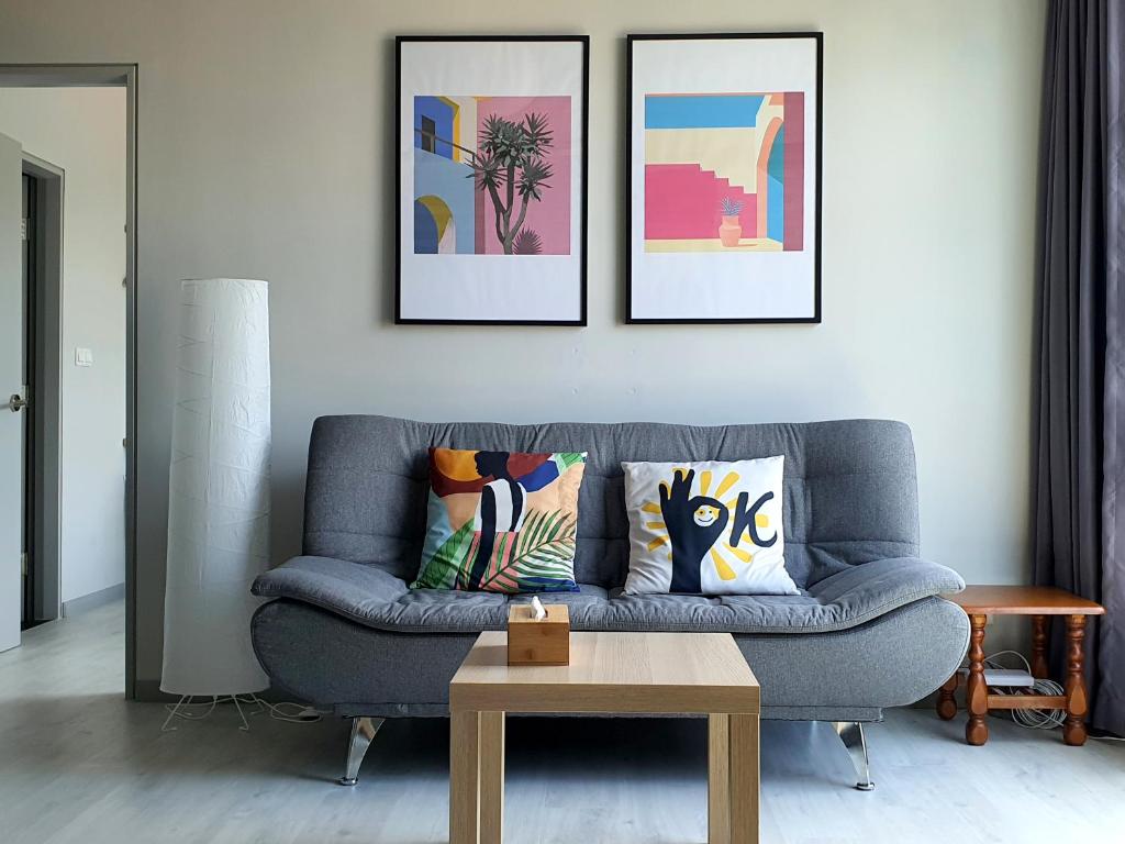 哥打京那巴鲁Jesselton Quay by Bunga Raya Homes的客厅配有蓝色沙发和三幅画作