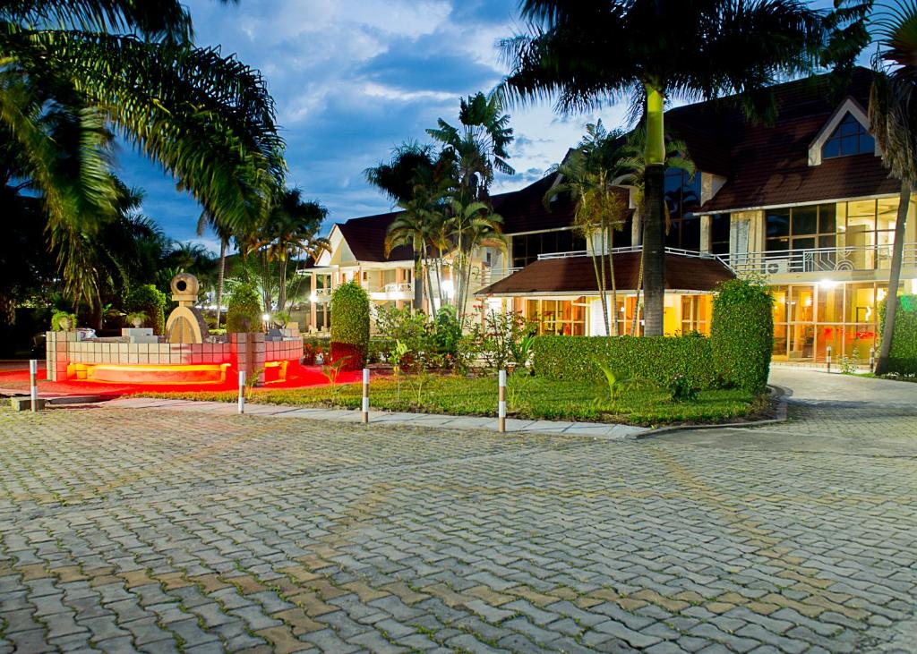 布琼布拉Hotel Safari Gate的砖车道前方的棕榈树房屋