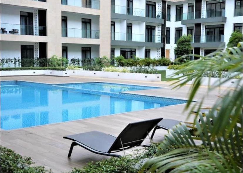 阿克拉Splendid Apartments - Embassy Gardens的一座带躺椅的游泳池位于大楼旁