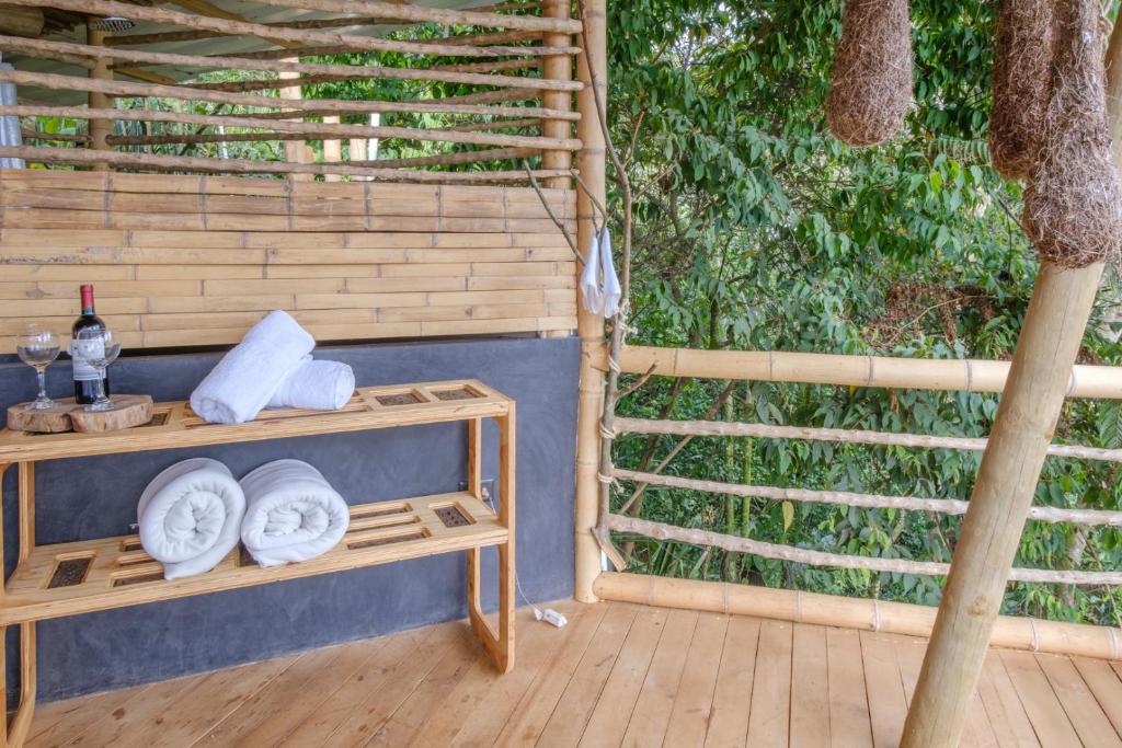 卡利Tabatinga, Hermosa Cabaña Privada en Reserva Natural - Cali Valle del Cauca的门廊配有带毛巾和一棵树的桌子