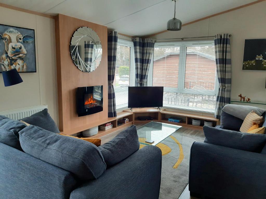 奥赫特拉德Sycamore Lodge Auchterarder的客厅配有2张蓝色沙发和壁炉