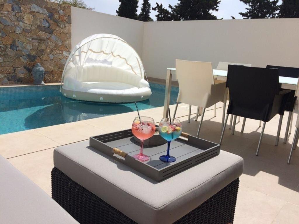 圣地亚哥德拉里贝拉Moderne frei stehende Villa mit Pool in Mar Menor的游泳池旁桌子上装有两杯酒的托盘
